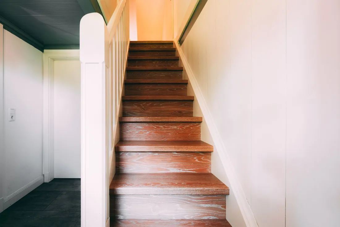 Escalier droit étroit en bois entre deux murs blancs (Prunelli-di-Fiumorbo, Haute-Corse)