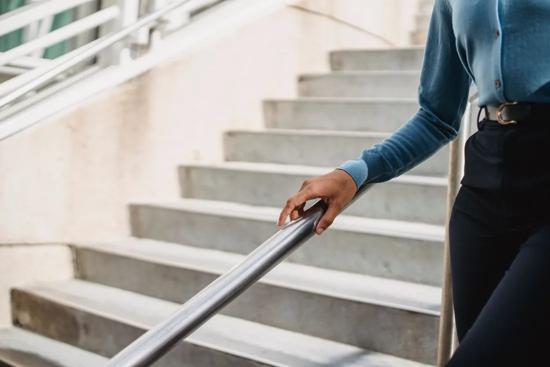 Main posée sur la rampe métallique d'un escalier extérieur en pierre (Beaumont-en-Véron, Indre-et-Loire)