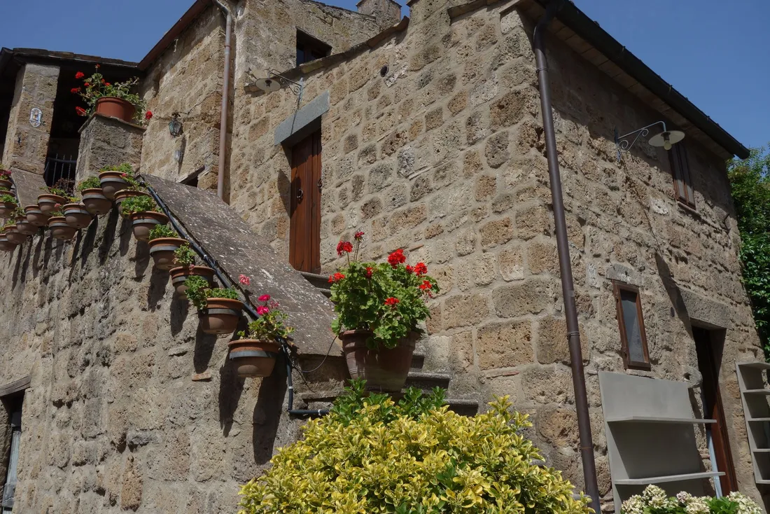 Maison en pierre avec un escalier extérieur fleuri le long de la façade (Gerzat, Puy-de-Dôme)